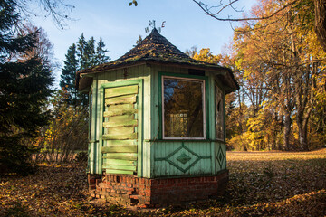 Small, green wooden gazebo in autumn evening.