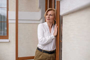 Pensive serene woman standing at the exterior door