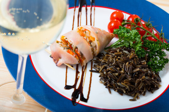 Image of stuffed squid with wild rice and cherry tomato on the plate indoors.