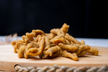 Close up view of kripik keripik usus ayam or gut chicken fried snack fritters crackers. traditional menu from Indonesia on wooden cutting board