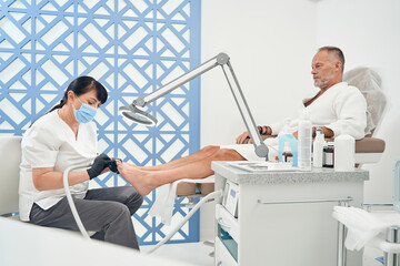 Man having hardware pedicure procedure in cosmetology salon