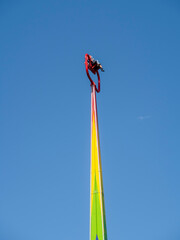 Two people in chairs high in the sky at the peak of the attraction in amusement park