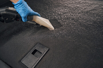 Hand holding portable vacuum cleaner in car interior