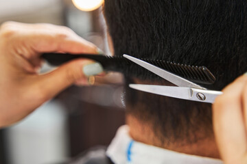 Scissors cutting off person hair under a comb