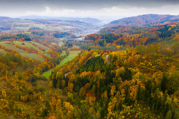 Aerial view of the autumn forest and road between the hills. Czech Republic