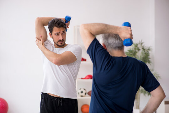 Young male instructor and old man doing sport exercises