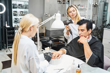 Beautician using cuticle pusher on man nails