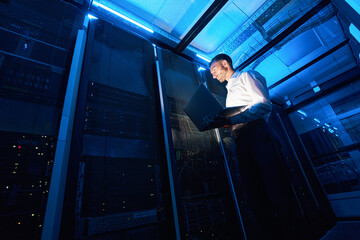 Network administrator using laptop while doing computer equipment checkup