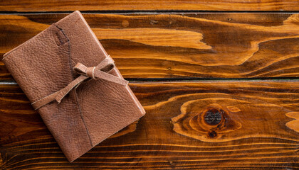 A diary book with leather cover and leather strap on wooden table.