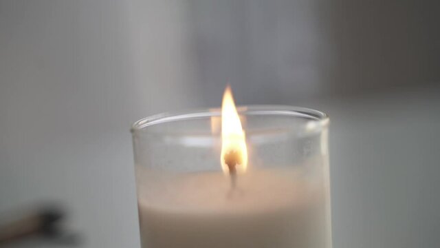 Close up shot of a candle flame in white background. Slow motion video of a burning candle on a white table and white background.