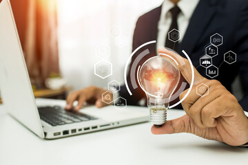 Business man holding light bulb on the Green background nature and writing on note book it for financial