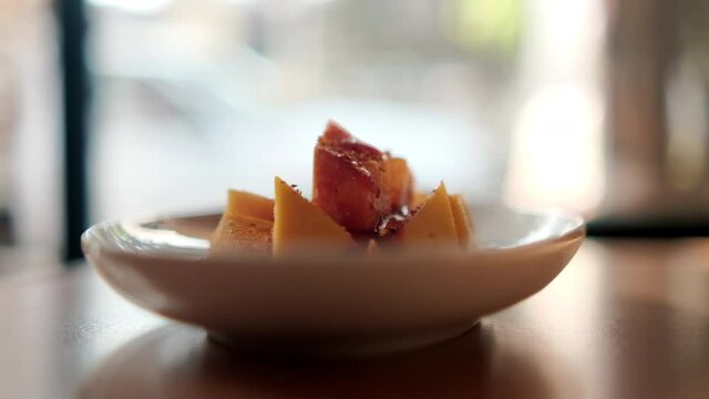 Plate of chopped mango with Mexican chamoy sauce and blurry background