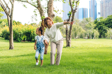 Fototapeta premium Portrait of happy love asian grandmother and little asian cute girl enjoy relax in summer park.Young girl with their laughing grandparent smiling together.Family and togetherness