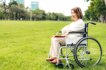 Fototapeta premium Senior adult elderly asia women sit on wheelchair and reading book outdoor