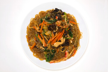 Korean traditional holiday food 'Japchae'. Consisting of cellophane noodles made from sweet potato starch, stir-fried with vegetables. Isolated on white background. Top view.
