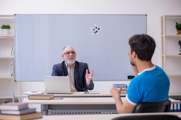 Old male teacher and young male student in front of whiteboard
