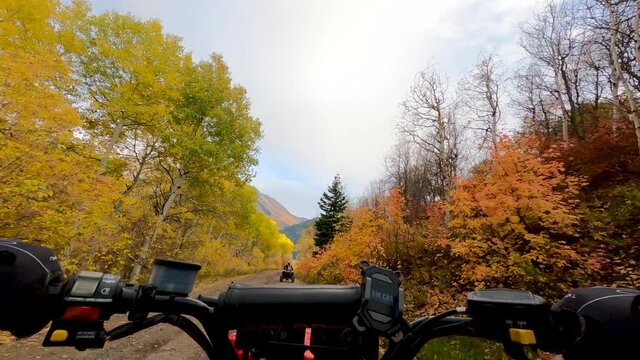 Friends riding four-wheelers along a Rocky Mountain road in autumn - first person view of beautiful fall colors