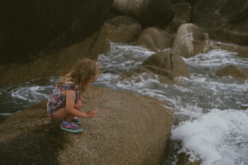 little girl sitting on big rocks