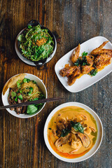 northern thai restaurant meal: skillet spinach with garlic and peanut sauce, deep fried chicken wings, spicy coconut prawn curry, victory egg noodles with BBQ pork