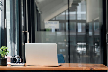 Rear view of laptop computer on wooden table in modern office room with copy space.
