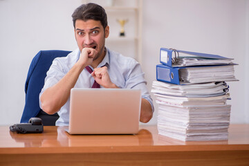 Naklejka premium Young businessman and too much work in the office