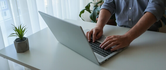 Banner close up young man working on laptop. Work from home minimalism interior