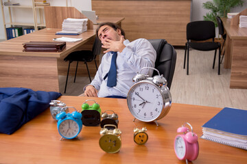 Young male employee sleeping in the office in time management co