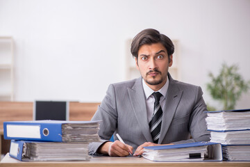 Young male employee unhappy with excessive work in the office