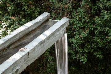 Naklejka premium water pouring down a concrete drainage in a mountain forest area