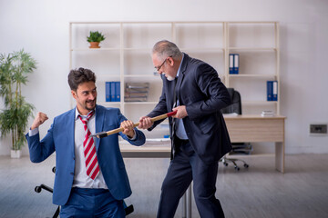 Old boss and young male employee in bullying concept