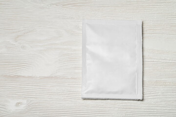 White paper sachet packet on wood table.