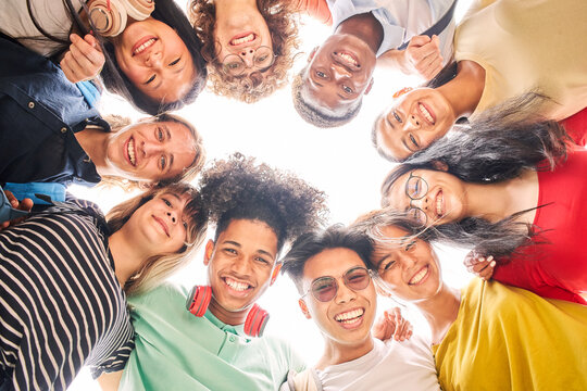 Low angle of a group of students are together, happy and smiling. Faces of young teenagers looking at camera, hugging.