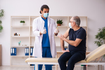 Fototapeta premium Old man visiting young doctor in covid-19 vaccination concept