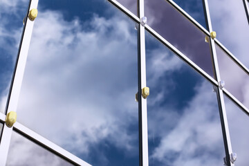 Architectural detail of the facade with multiple reflections of other buildings and the sun. Modern building. Architecture background