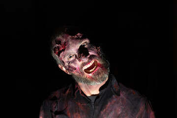 Zombie man portrait in darkness with makeup for halloween party
