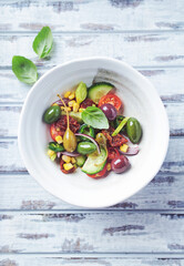 Simple Salad with Green and Kalamata Olives, Cucumber, Cherry and marinated Tomatoes, Capers and Jalapeno Pepper. Bright wooden background.  Top view.  