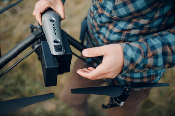 Man pilot checking quadcopter drone battery replacement and charging before aerial flight and filming