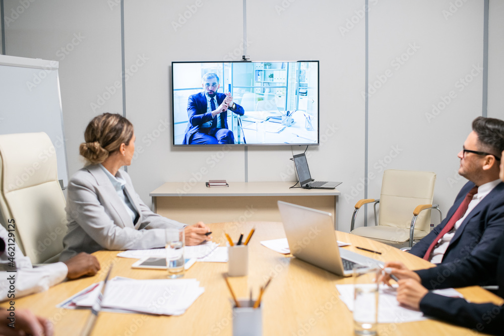 Poster group of brokers listening to mature businessman on large display during webinar or video training