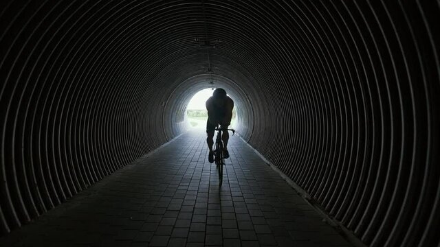Triathlete rides a cutting bike, pro cyclist rides in a tunnel, athlete training for race, 4k slow motion.