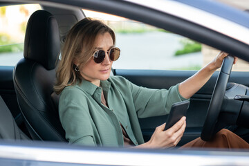 Young serious blond woman scrolling in smartphone while looking for destination point