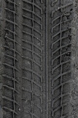 Traces of car tire tread in the ground. Pattern. Dark abstract background. Imprint of wheels. Textured soil. Drawing tires