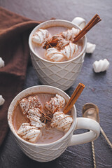 Cups of hot cocoa drink and marshmallows on dark background
