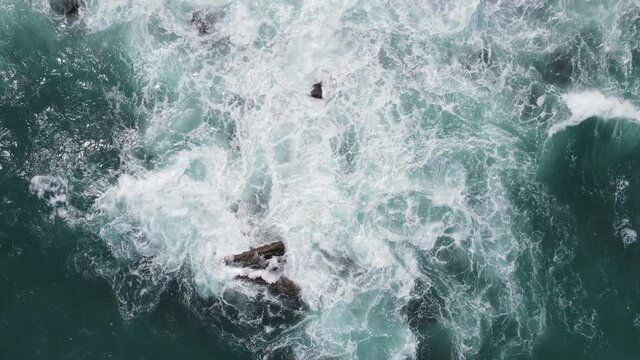 Top view of Sea waves crash on the rocks of the coast creating an explosion of water