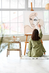 Fototapeta na wymiar Young female artist painting in workshop