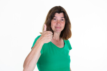 Middle age woman pointing thumb up aside copy space smiling happy