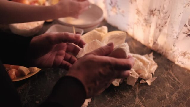 A man cleans a piece of pomelo with his hands in the kitchen