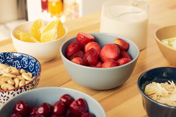 Group of bowls containing ingredients for homemade smoothie on wooden kitchen table