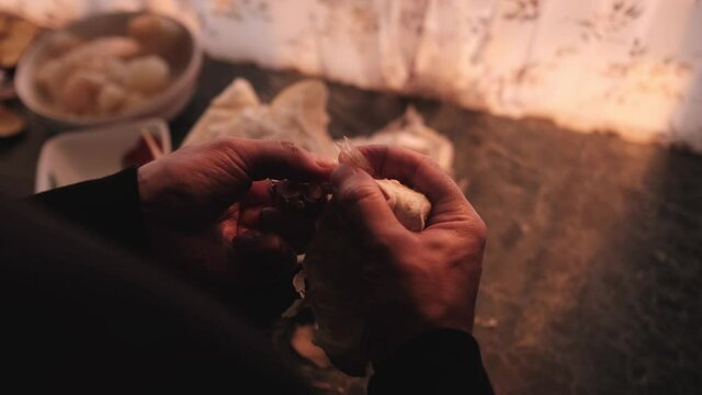A man cleans a piece of pomelo with his hands in the kitchen