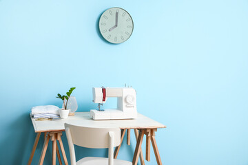 Tailor's workplace with sewing machine near blue wall