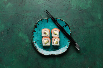 Stylish plate with delicious sushi rolls and chopsticks on color background